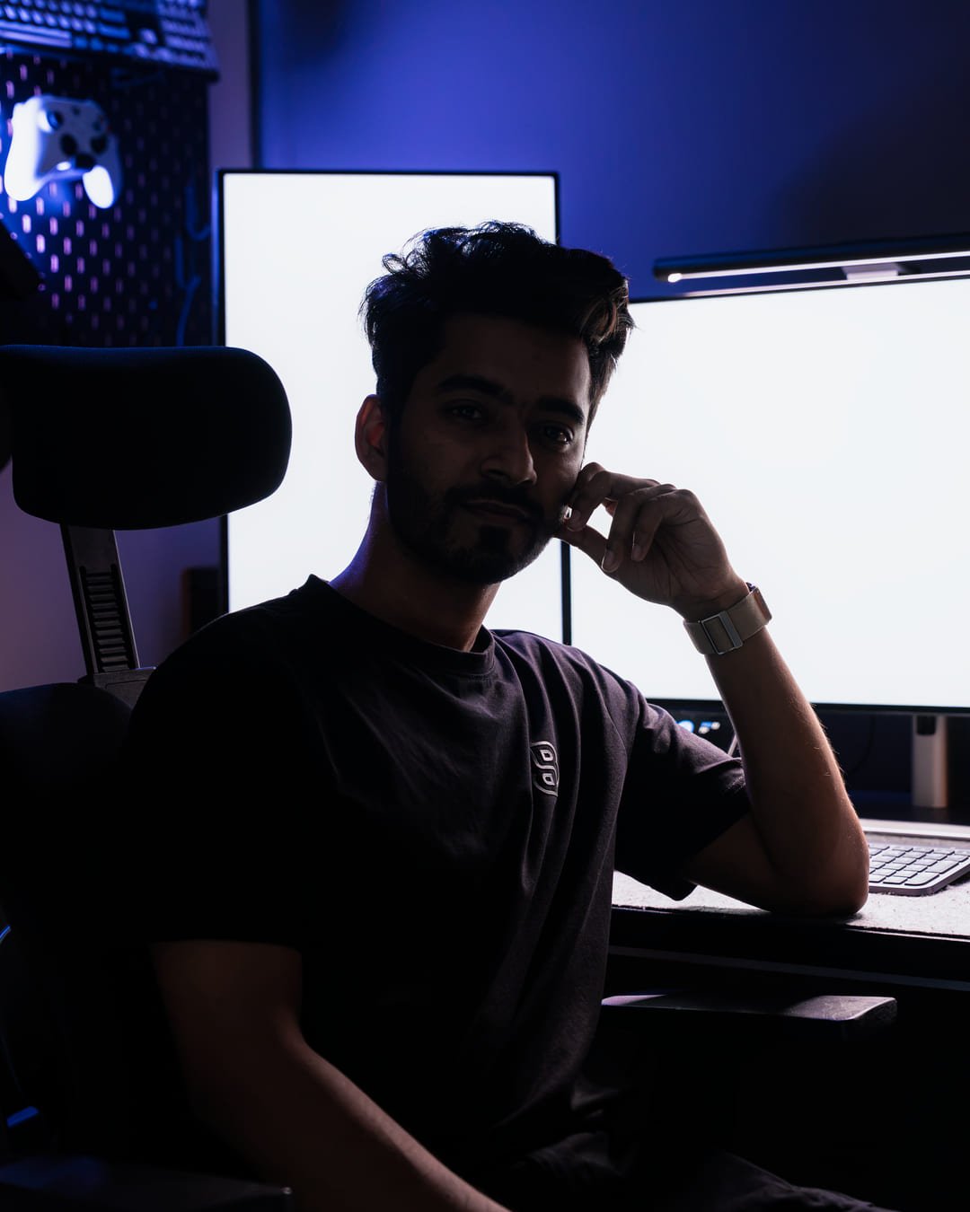 Raihan Ghorami seated at his workstation in low blue light, looking at the camera