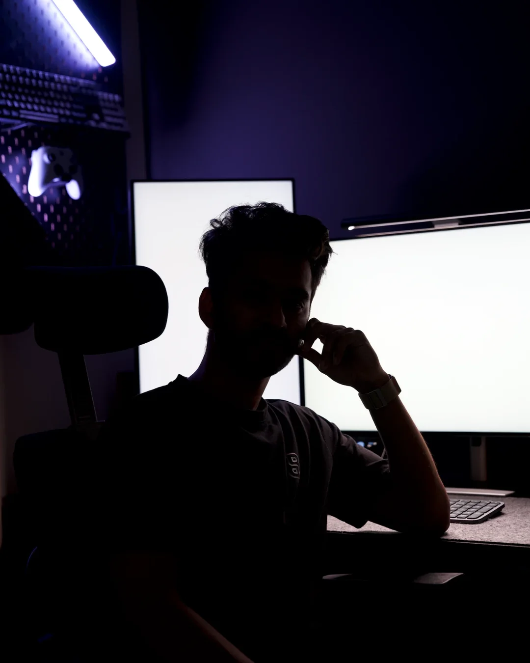 Raihan Ghorami at his editing desk at night, two bright monitors behind him, hand at his chin